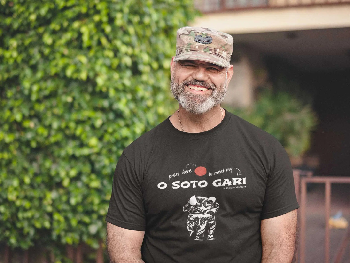Man in a camo cap wearing a black 'O Soto Gari Press Here' Judo T-Shirt, a bold and sporty choice for judo fans.