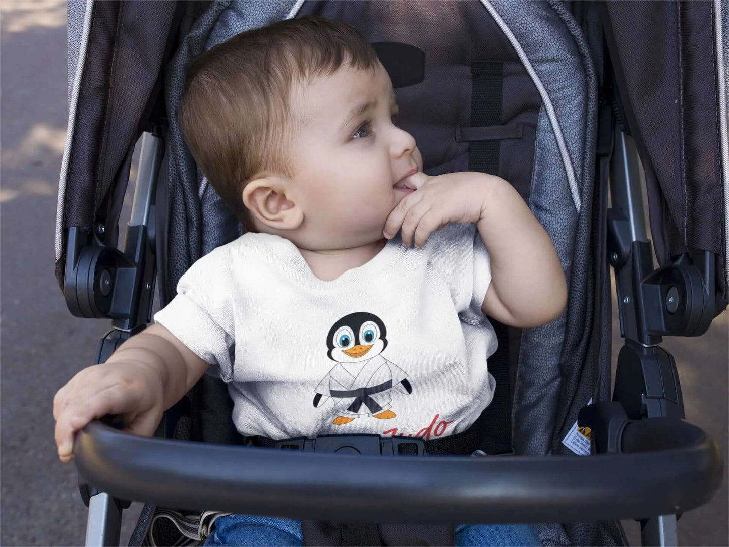 Baby wearing a white Judo bodysuit with a cute penguin design and 'I Love Judo' text, seated in a stroller. Perfect for toddlers.