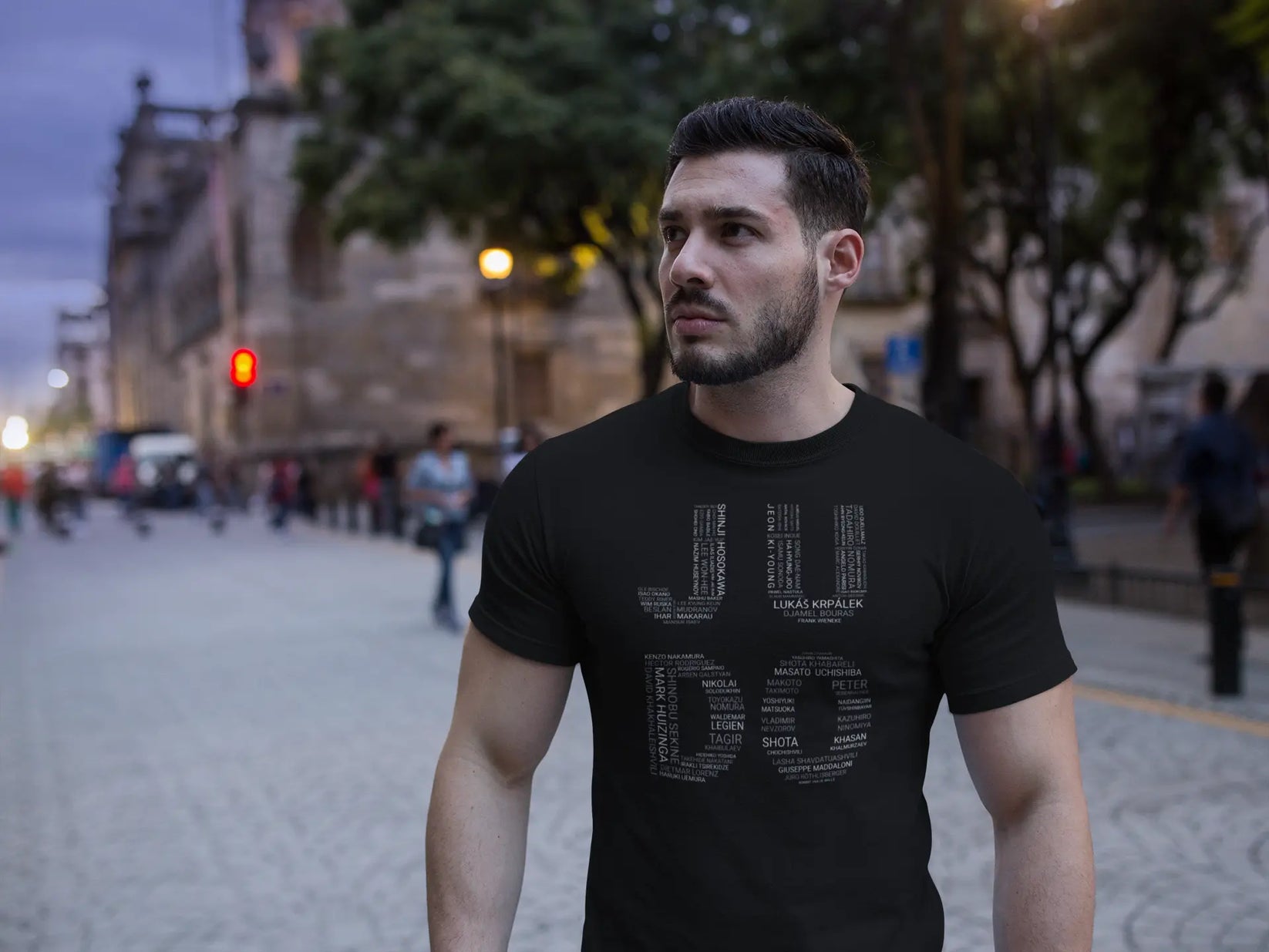 Model wearing the Judo Olympic Winners T-Shirt in a casual outdoor setting, showcasing the bold design of Olympic judo legends' names.