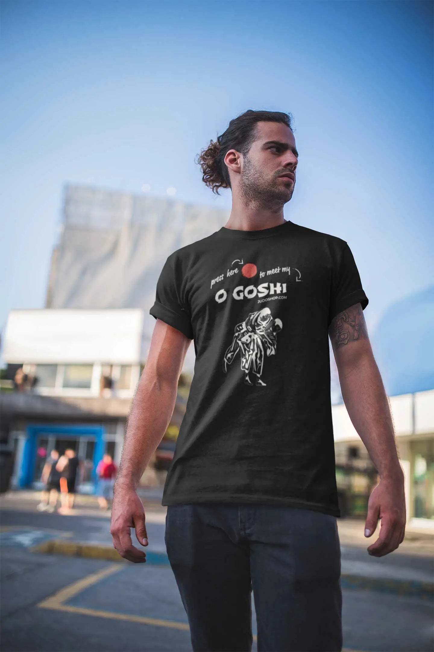 Man standing outdoors in a black Judo T-Shirt with 'Press Here to Meet My O Goshi' design, styled for everyday casual wear.