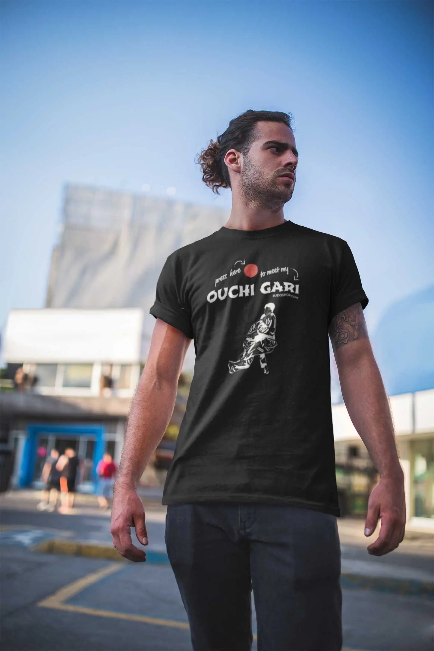 Man standing outdoors in a black 'Ouchi Gari Press Here' Judo T-Shirt, showcasing a modern and athletic style.