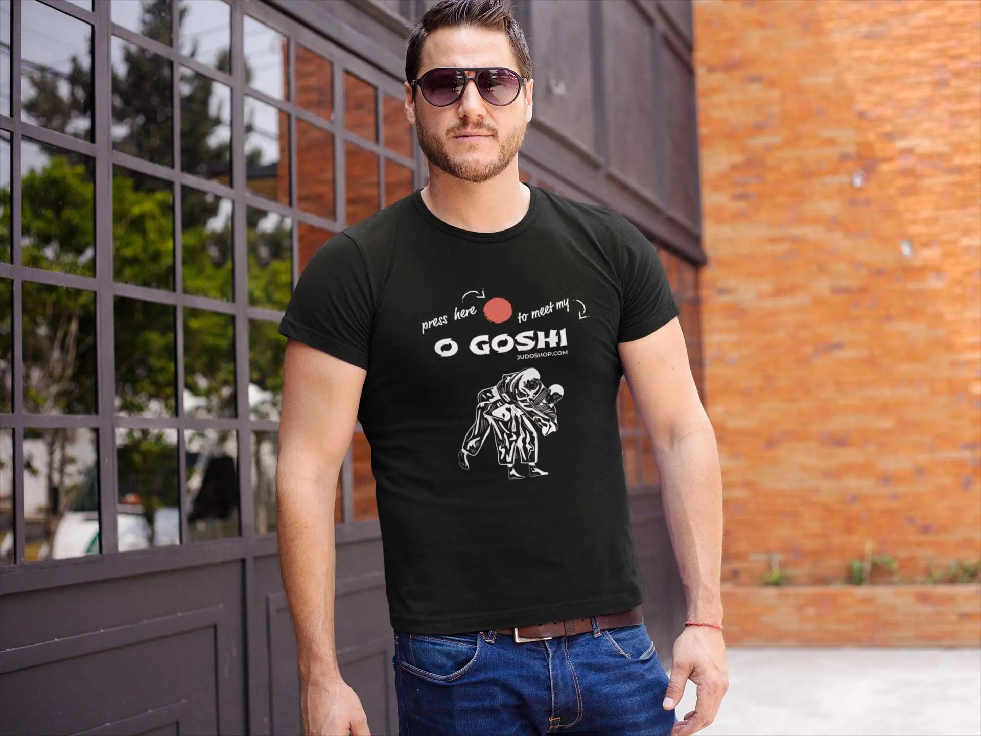 Man standing outdoors in a black Judo T-Shirt with 'Press Here to Meet My O Goshi' design, styled with sunglasses for a modern look.