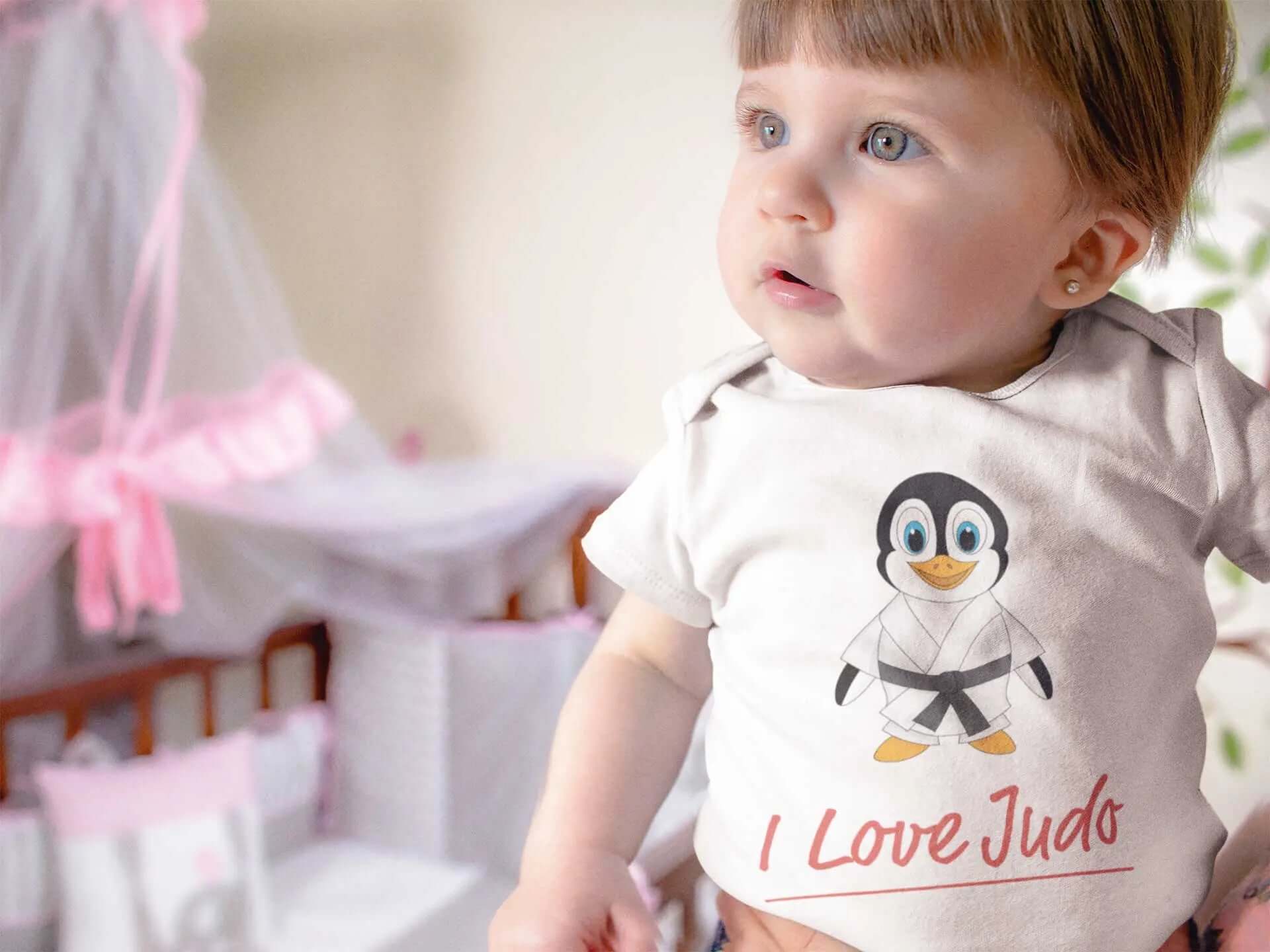 Adorable baby wearing a white bodysuit featuring a cute penguin in a judo outfit with the text 'I Love Judo,' perfect for toddlers.