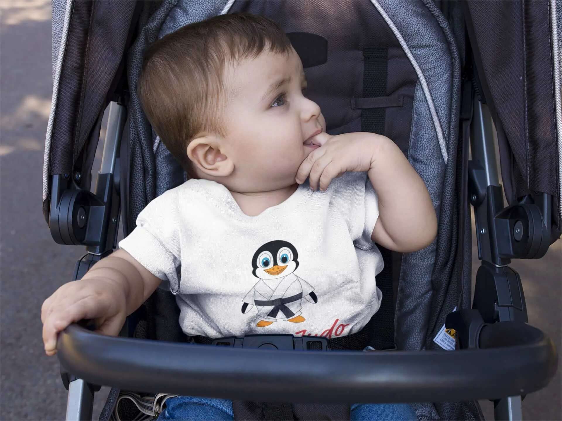 Baby wearing a white Judo bodysuit with a cute penguin design and 'I Love Judo' text, seated in a stroller. Perfect for toddlers.
