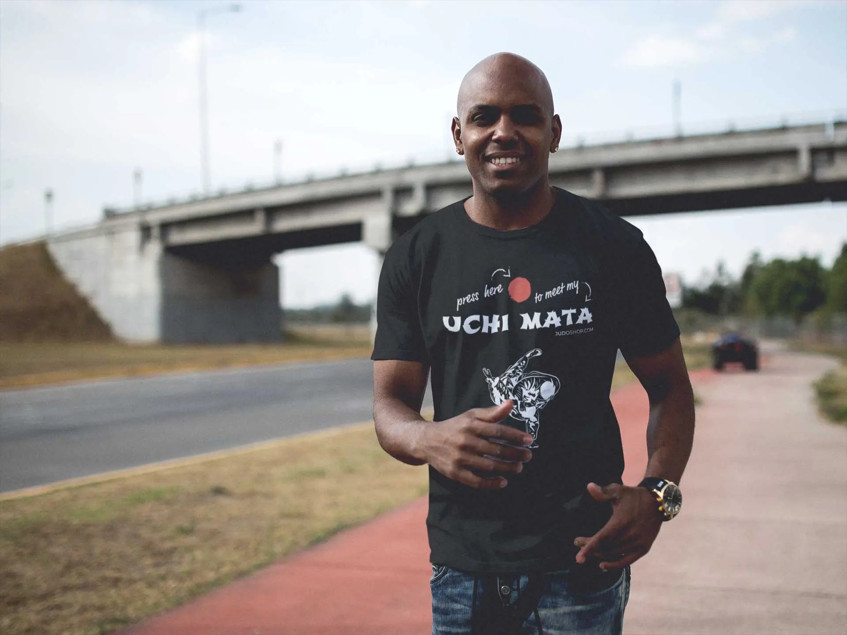 Man jogging outdoors in a black Judo T-Shirt with 'Press here to meet my Uchi Mata' design, combining fitness and style.
